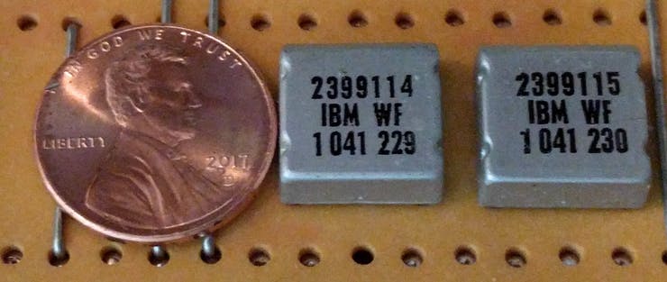 Two IBM SLT modules, with a penny for scale. Each module contains semiconductors (transistors or diodes) and printed resistors wired together, an alternative to integrated circuits.