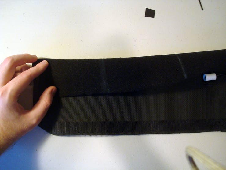 Take the upper edge of the belt (The edge without the velcro on it) and fold it over the tactors.